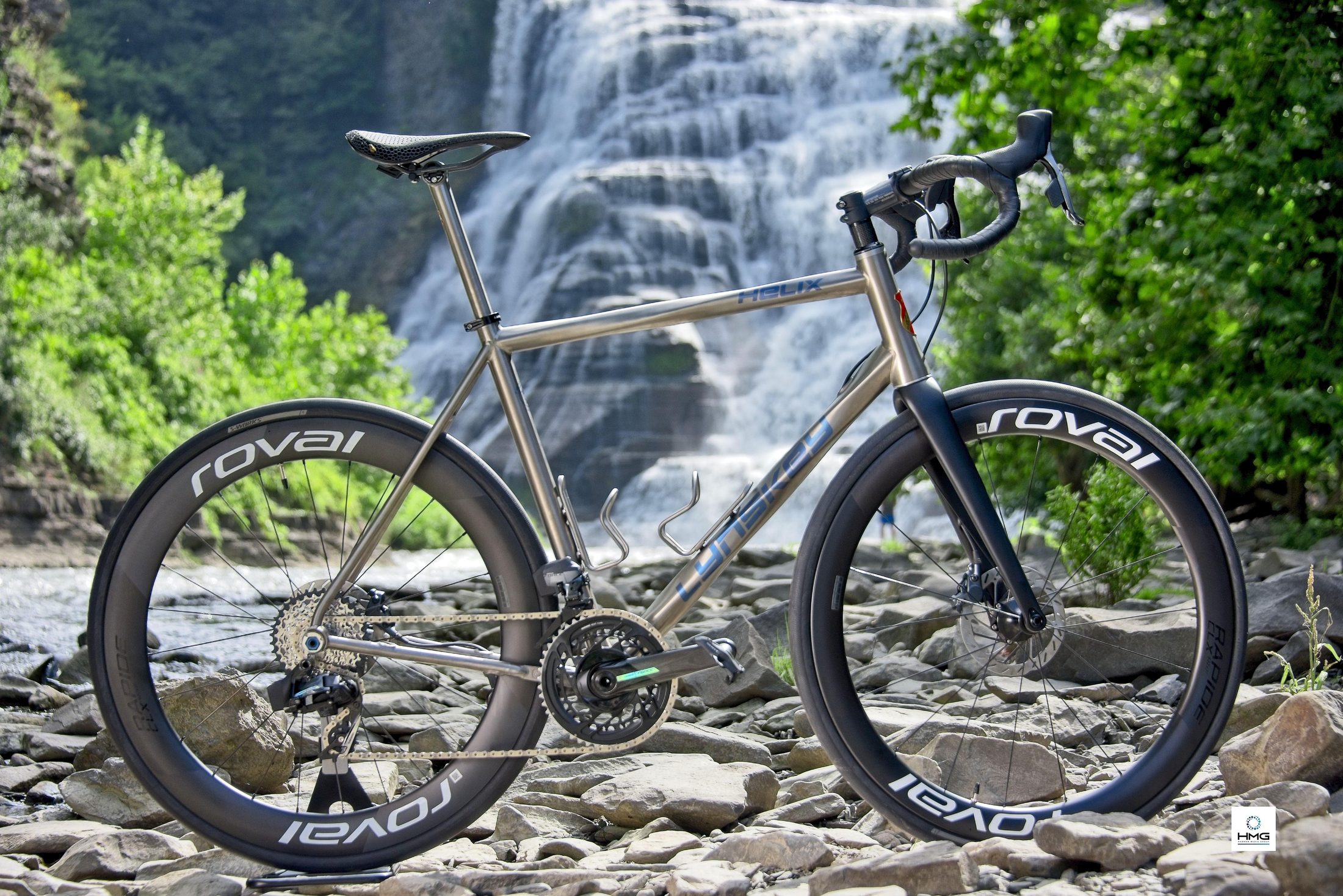 Bicycle posed on rocks in front of a waterfall
