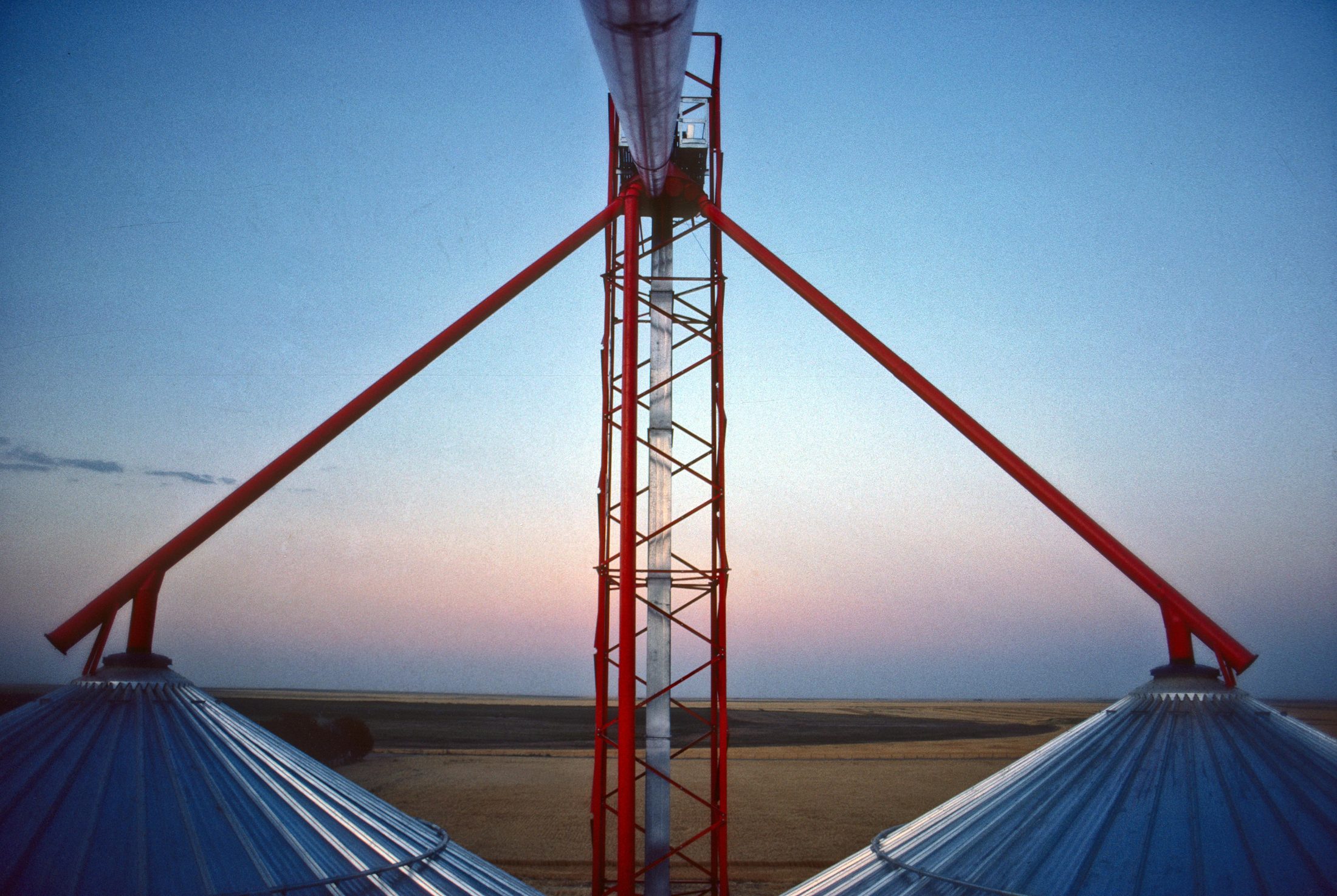 Grain bin ladder at dusk, sky glowing pink