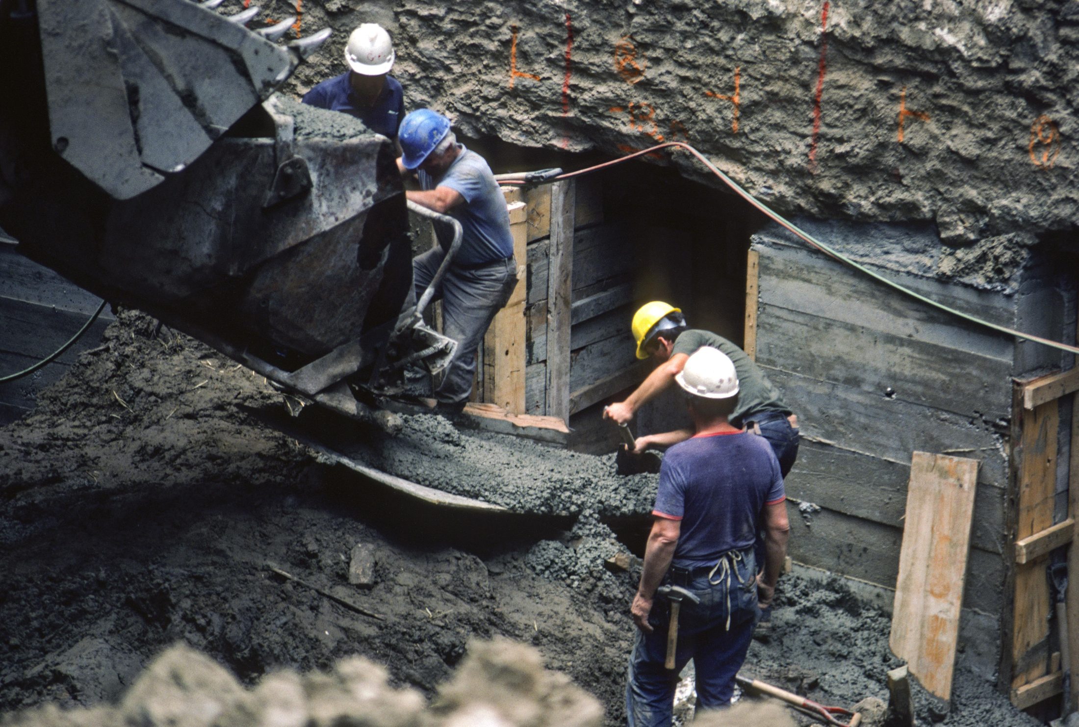 Workers pouring concrete into a foundation excavation