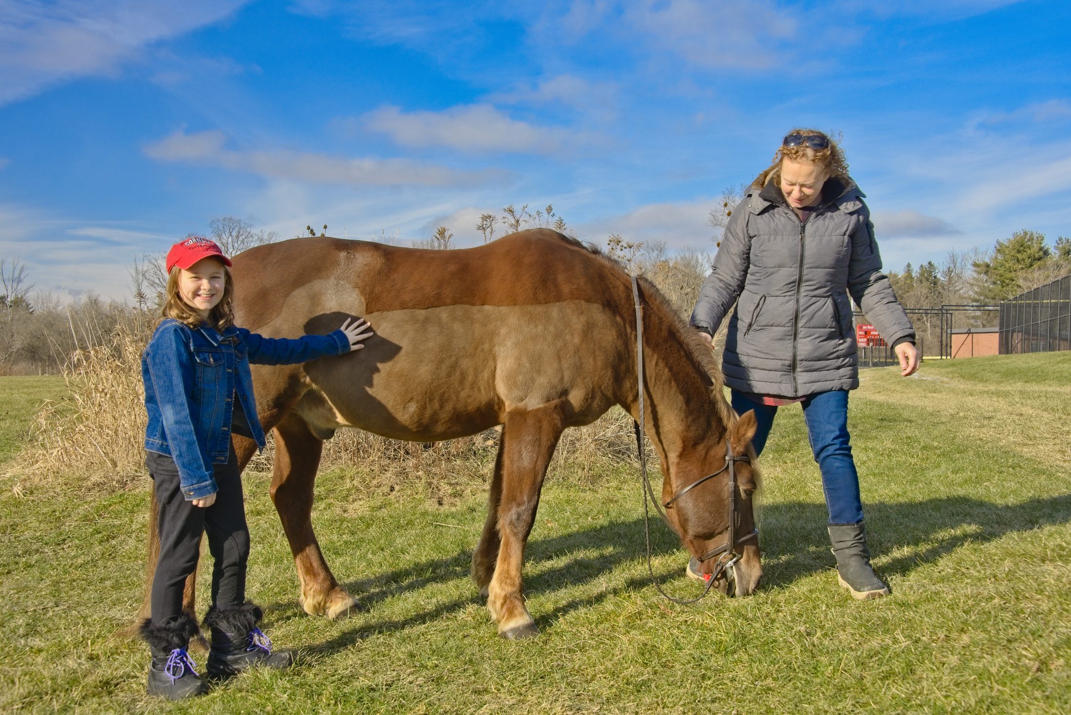 Young rider and her mother posing with their horse, portrait for a Sidelines Magazine feature on the Cornell Equestrian Team