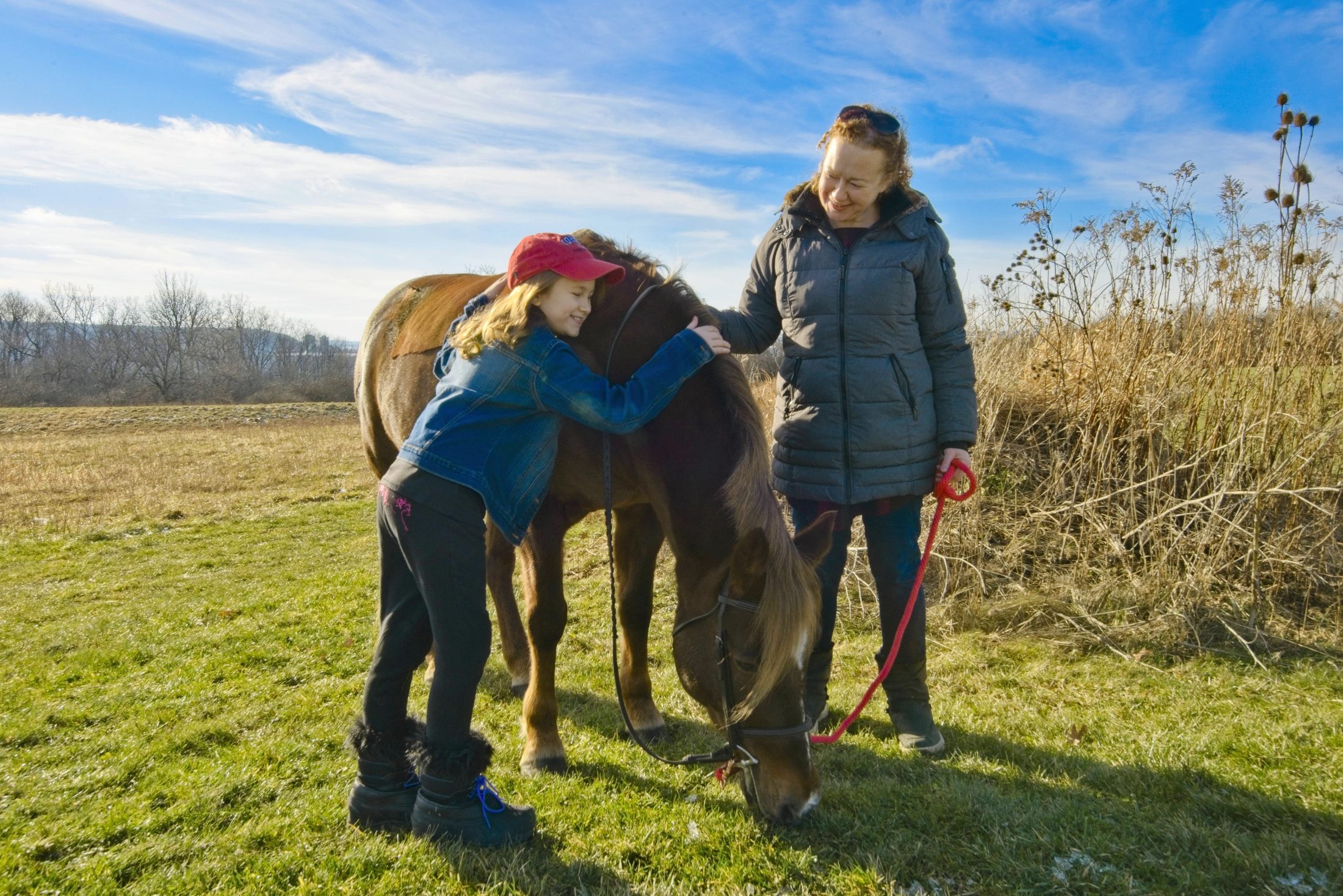 A young rider and her mother embracing their horse, Sidelines Magazine feature