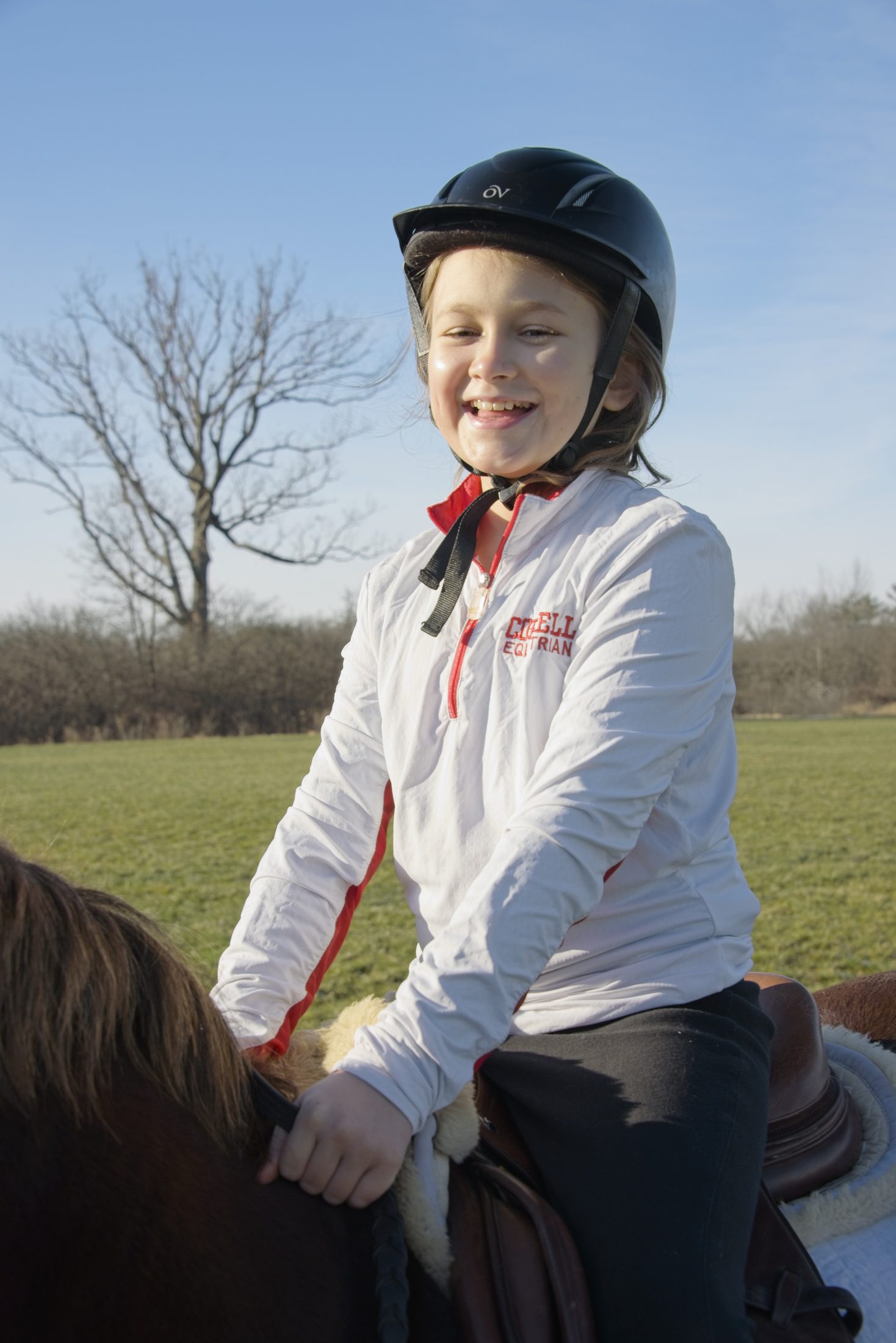 Young rider on horseback wearing a Cornell Equestrian shirt, Sidelines Magazine feature