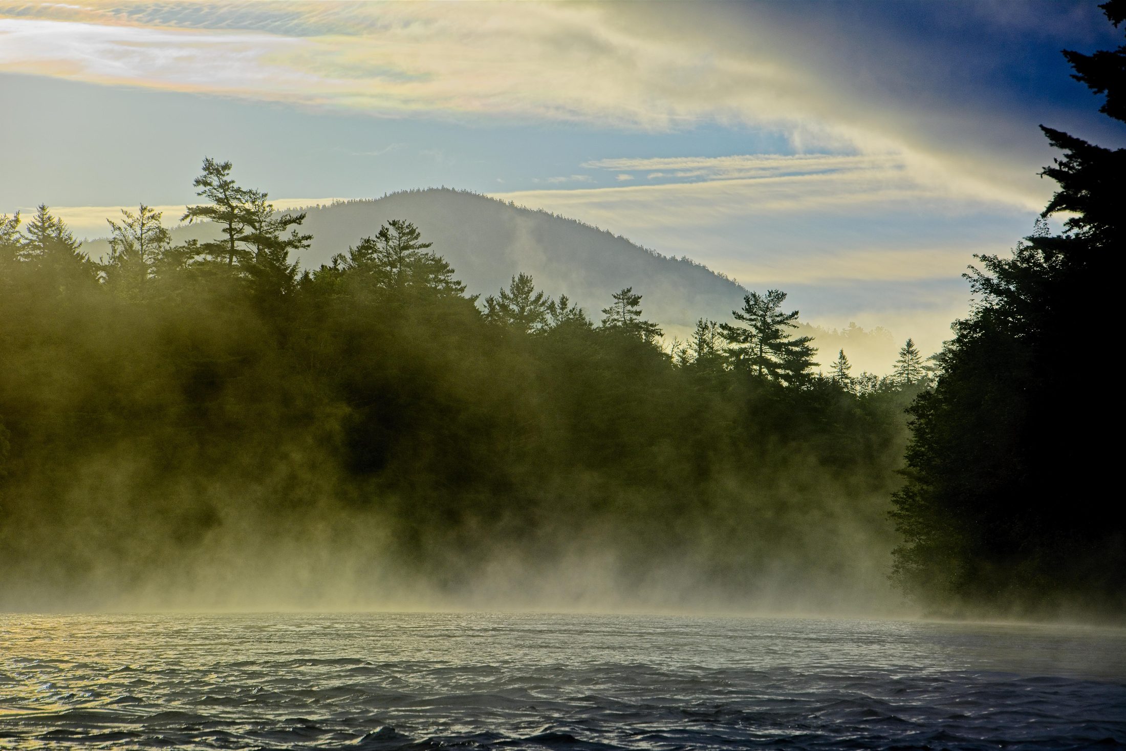 Mist rising off a lake at sunrise along the Golden Road, mountain behind
