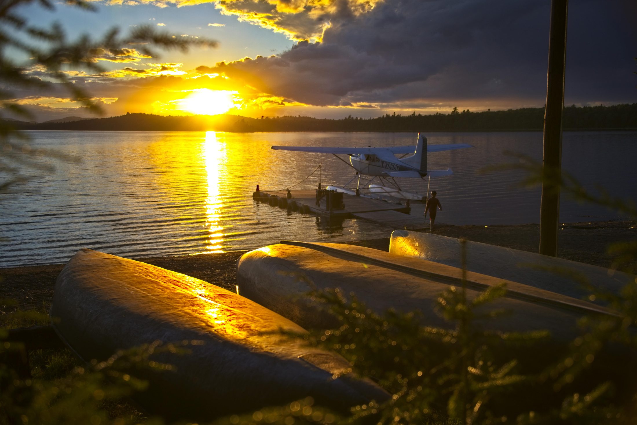 Seaplane at sunset, dock with canoes
