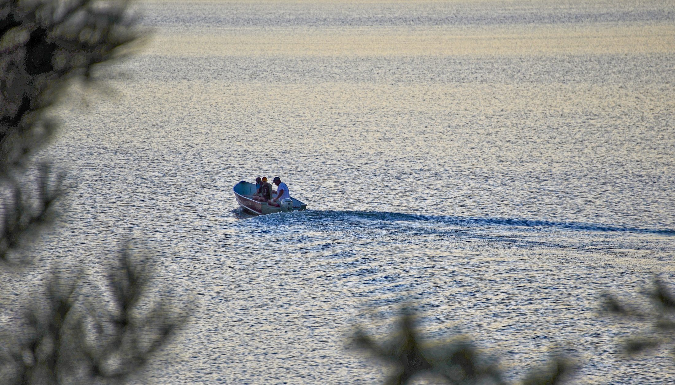 Small motorboat crossing Millinocket Lake at dusk